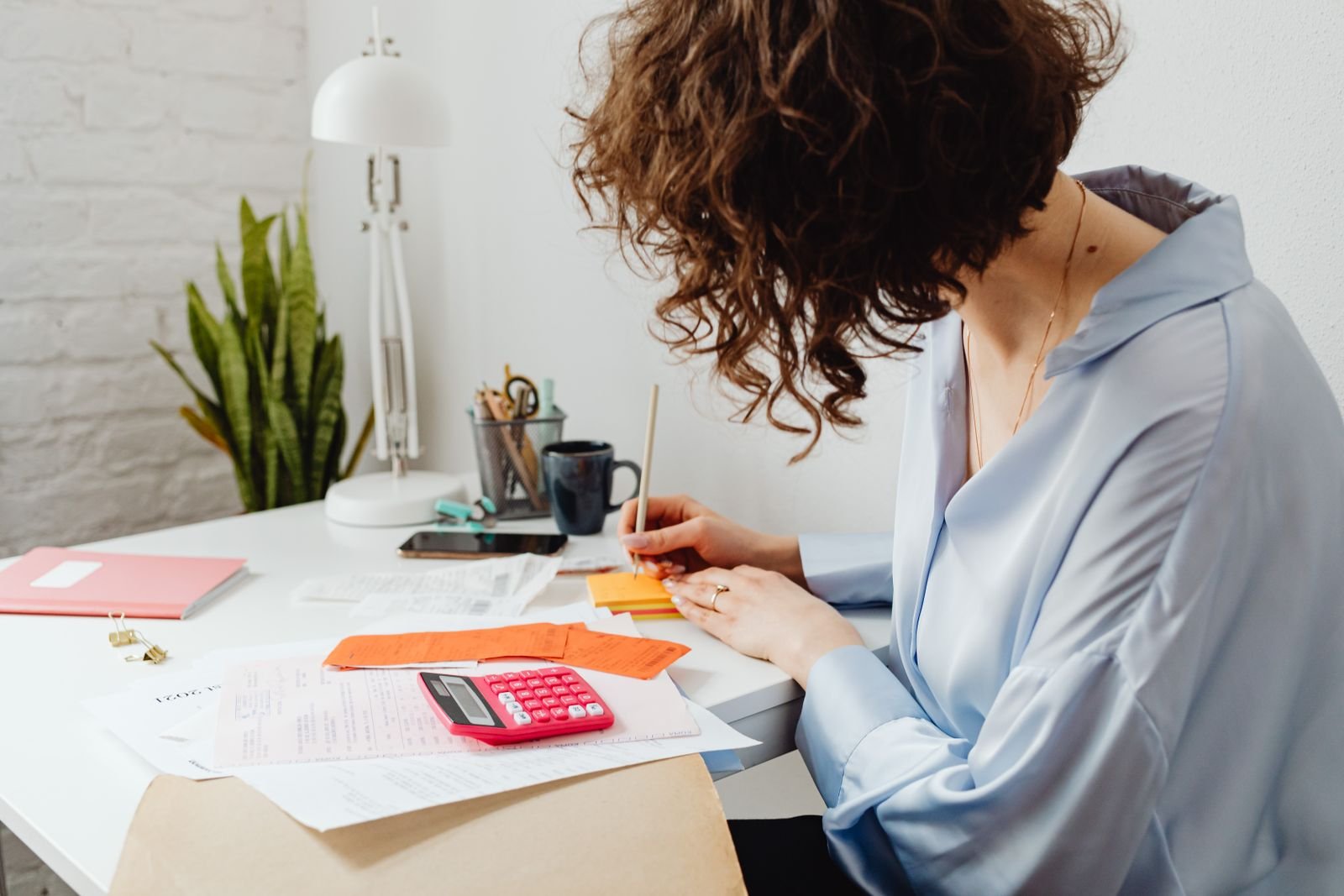 Mulher calculando em caderno como dividir contas com renda que varia junto do parceiro