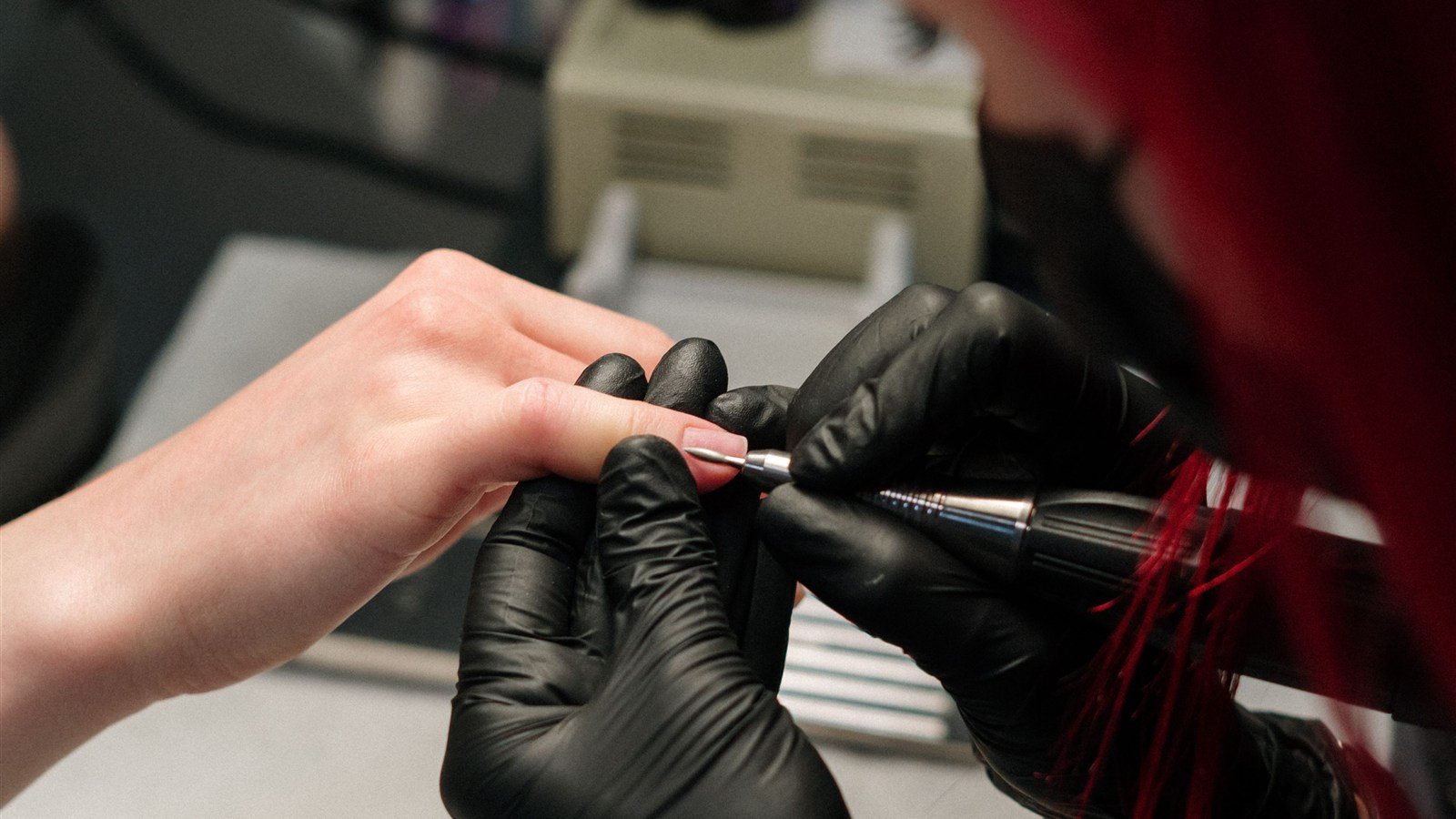 Manicure atendendo cliente, fazendo as unhas com esmalte e utensílios de manicure