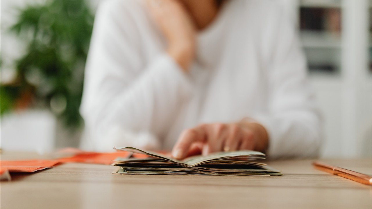Mulher contando e organizando notas de dinheiro sobre a mesa para planejar o orçamento