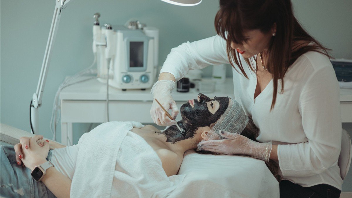 Esteticista autônoma atendendo cliente com aparelho de estética no salão