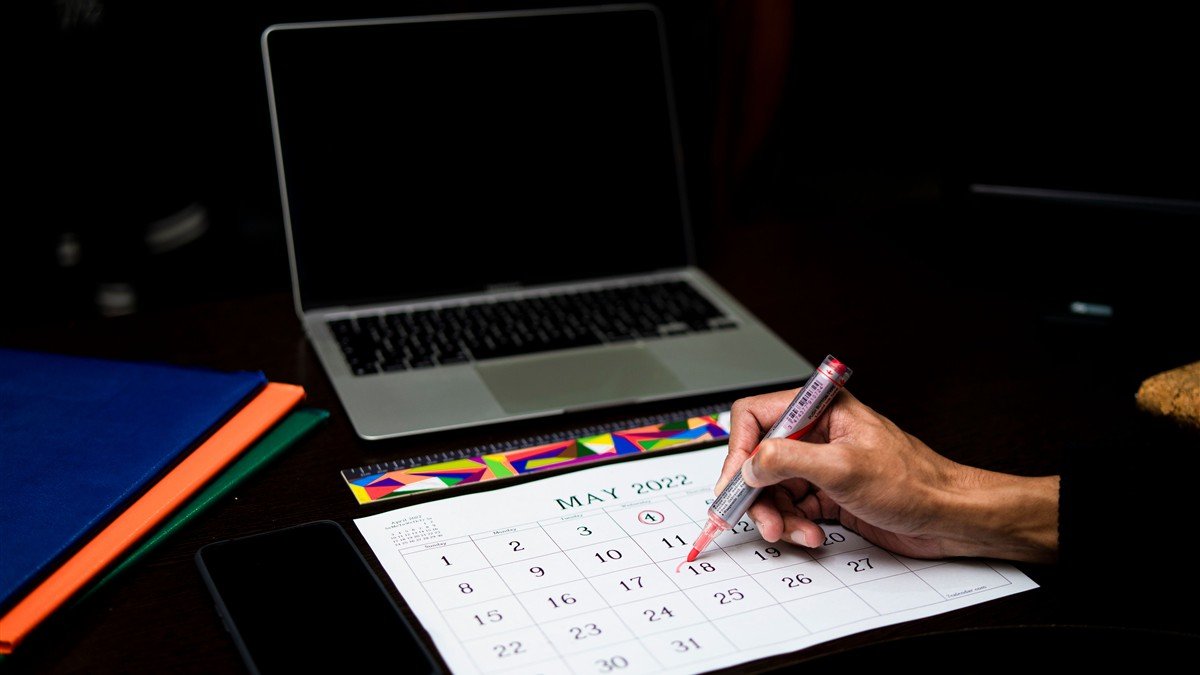 Mulher autônoma planejando as férias no calendário com o celular na mão
