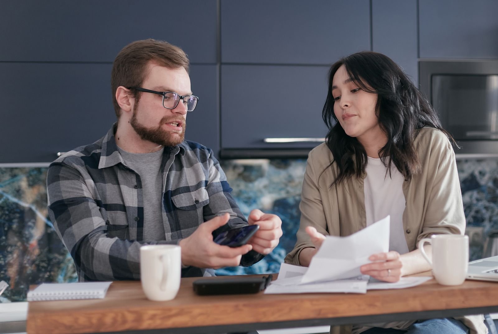 Casal conversando sobre como dividir contas com renda que varia à mesa da cozinha