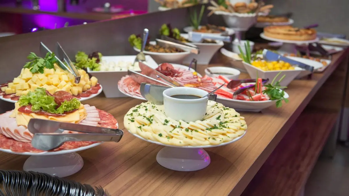 Cozinheira de eventos organizar renda montando mesa de buffet com bandejas de comida
