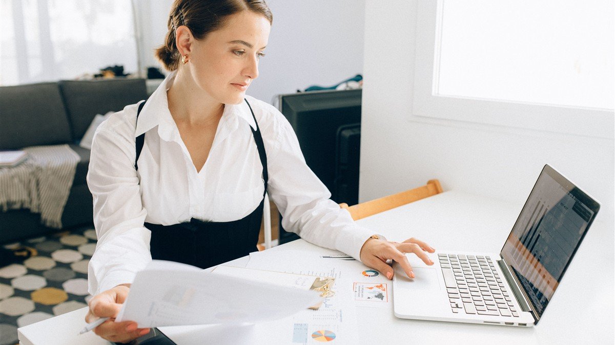 Representante comercial conferindo nota fiscal e comissão recebida no notebook
