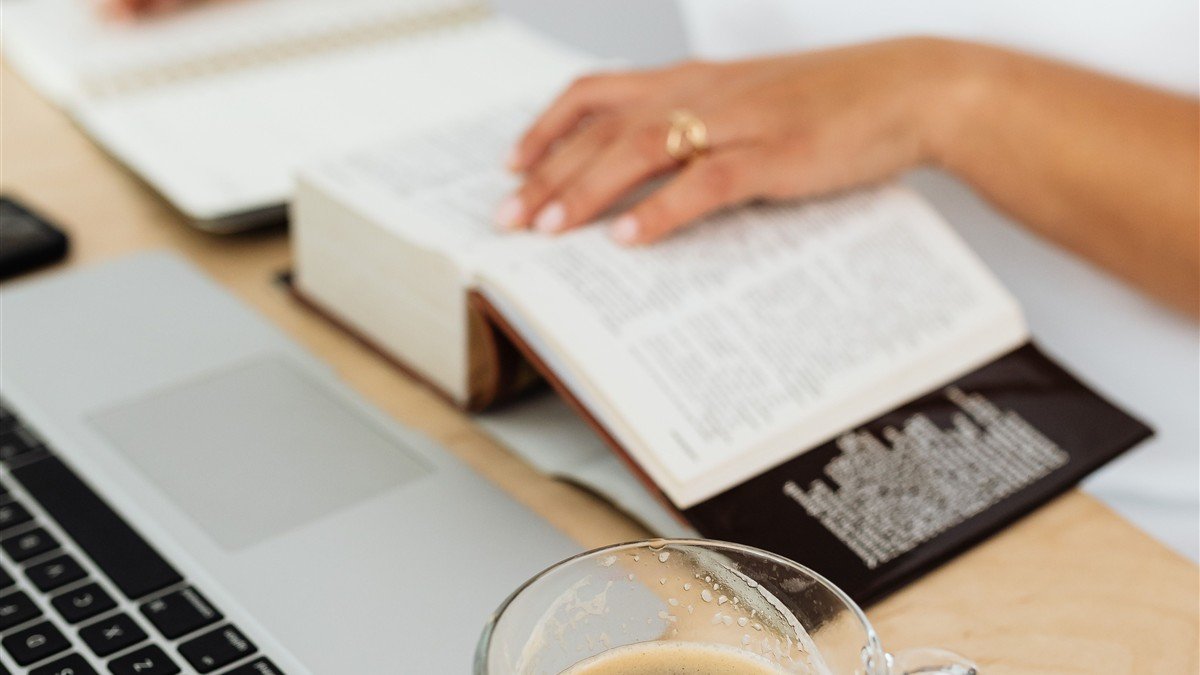 Tradutora freelancer receber em dólar trabalhando com dicionário e notebook na mesa