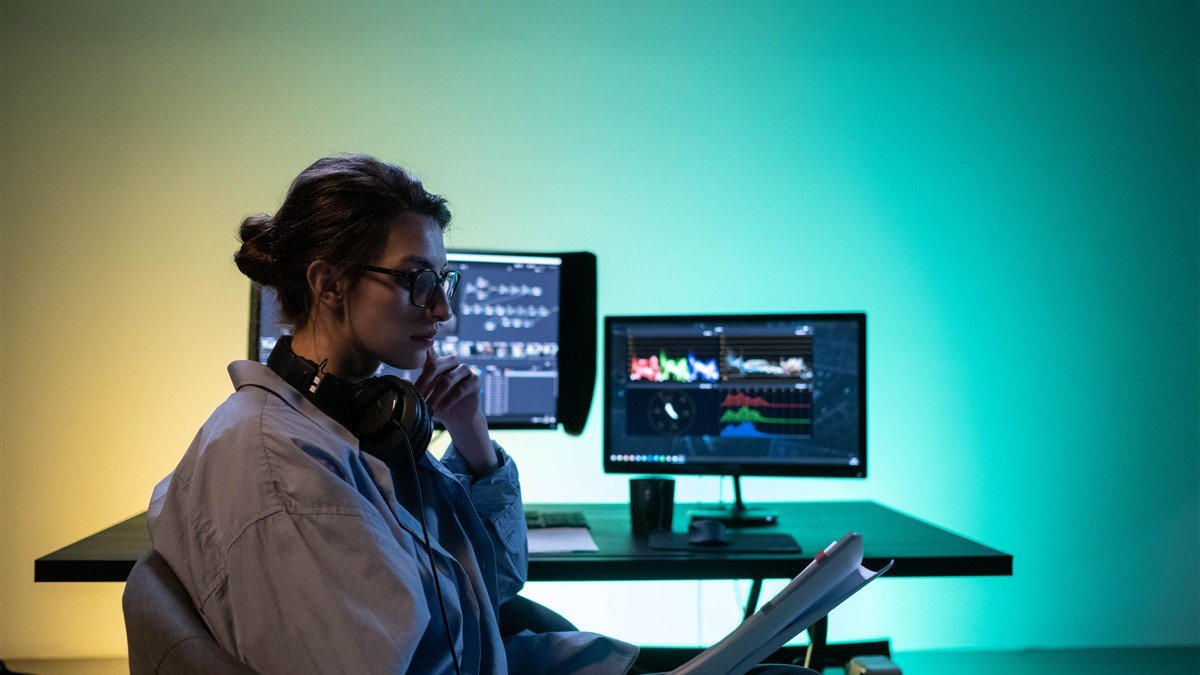Editora de vídeo trabalhando na timeline de edição em dois monitores